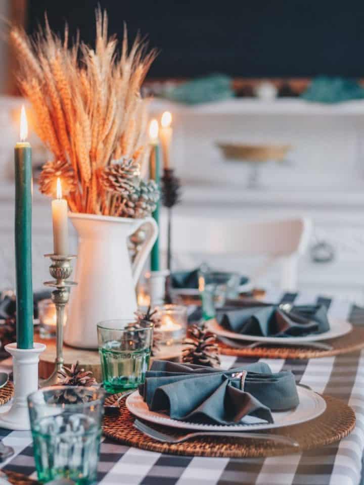 The family dinner table is set for a special meal with pretty napkins, candles, and a vase filled with wheat.
