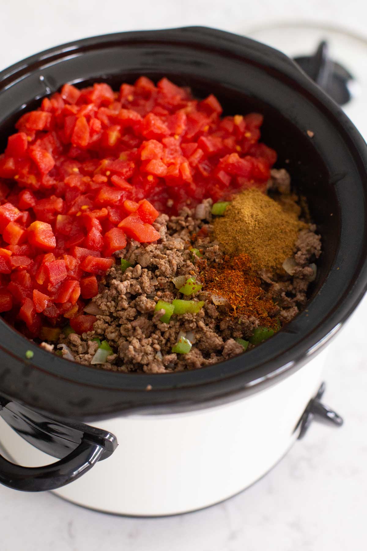 The diced tomatoes and seasonings have been added to the crockpot.