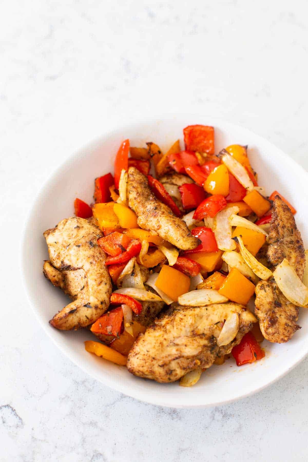 The big serving bowl is filled with the cooked chicken and peppers.