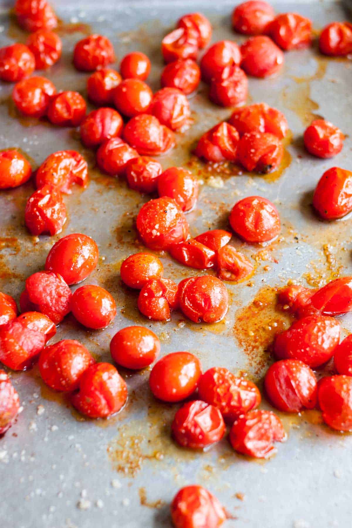 The roasted cherry tomatoes have been cooked on a large baking sheet.