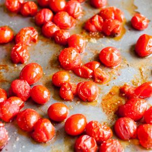The roasted cherry tomatoes have been cooked on a large baking sheet.