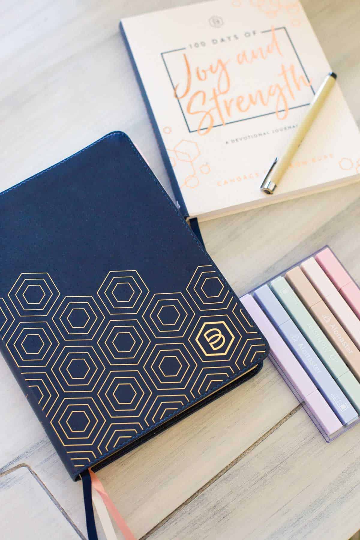 A Bible, a devotional, highlighters and a pen are on the table.