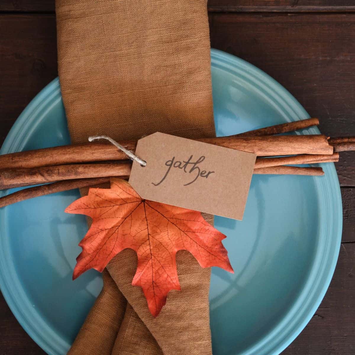 A blue plate has a brown napkin and an orange leaf with a tag that says "gather".