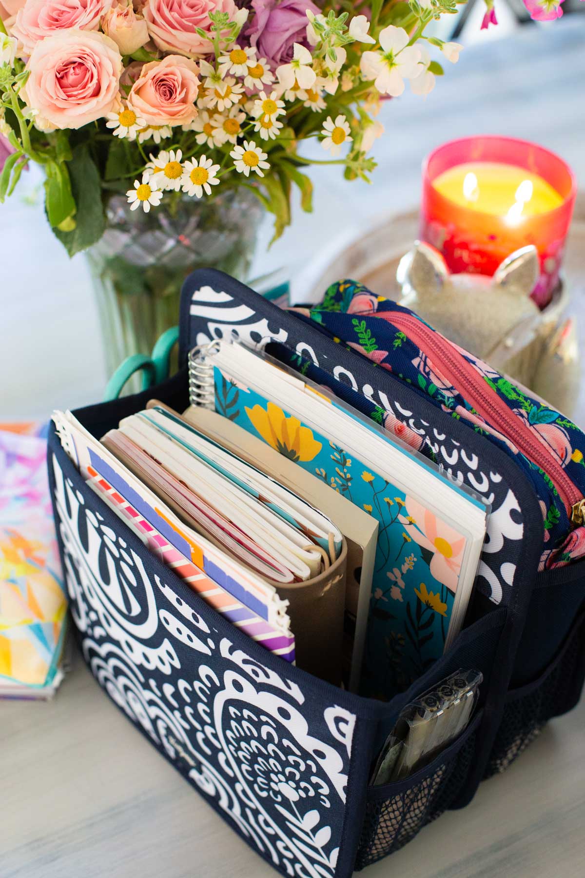 The basket is filled with the journals and planner and is sitting next to fresh flowers and a candle.