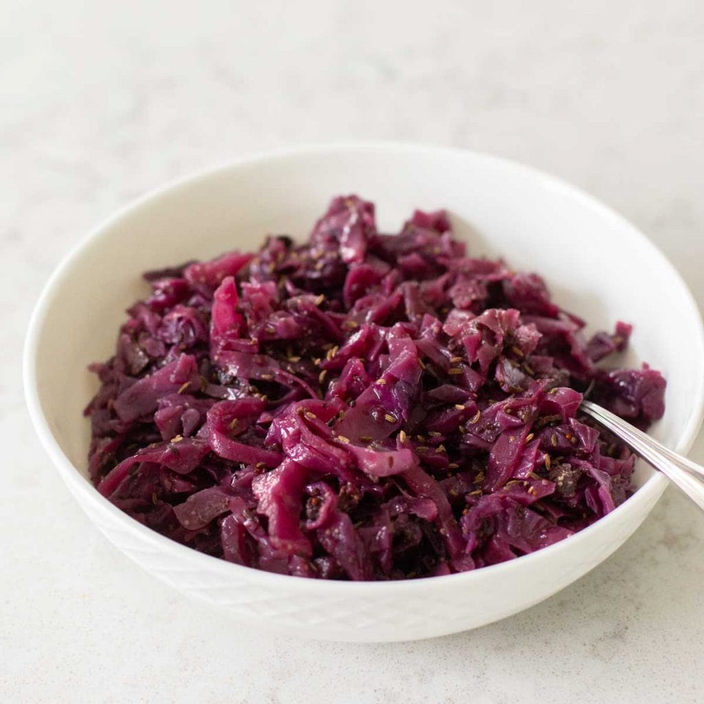 A white bowl filled with shredded cooked red cabbage.