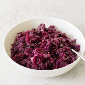 A white bowl filled with shredded cooked red cabbage.