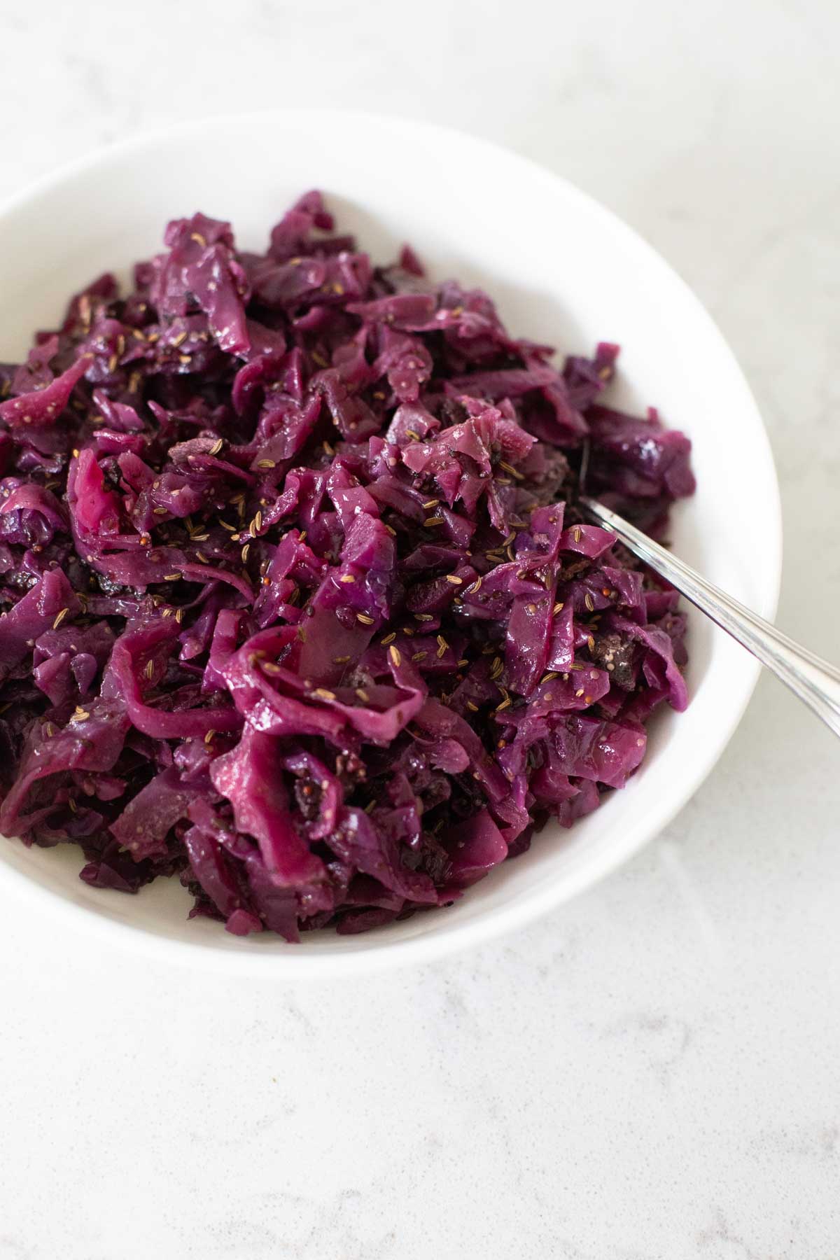 A white bowl filled with shredded cooked red cabbage.