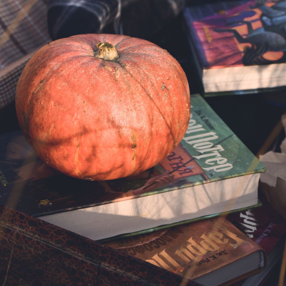 A stack of Halloween books with a pumpkin on top.