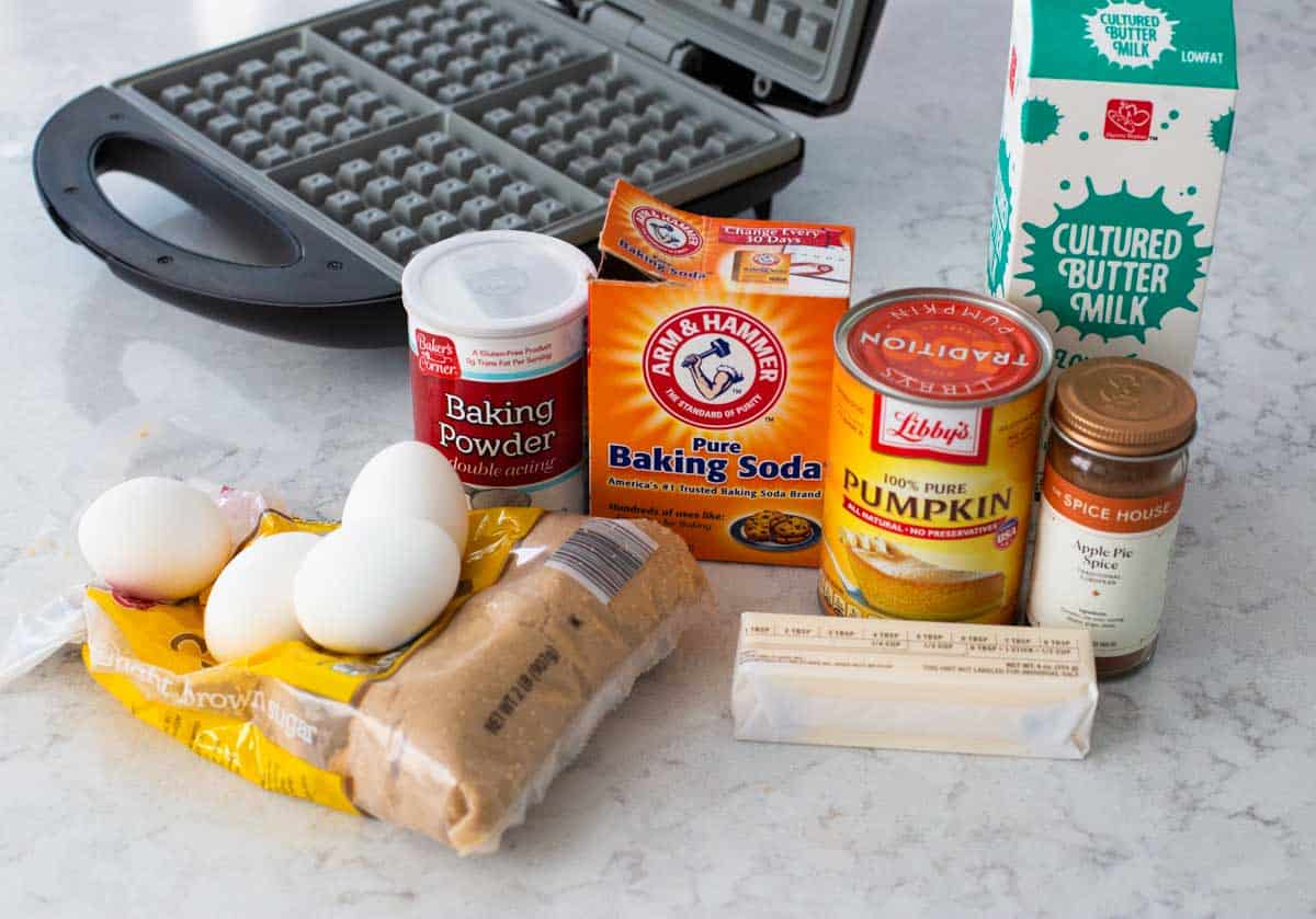 The ingredients to make homemade pumpkin waffles are next to the waffle maker.