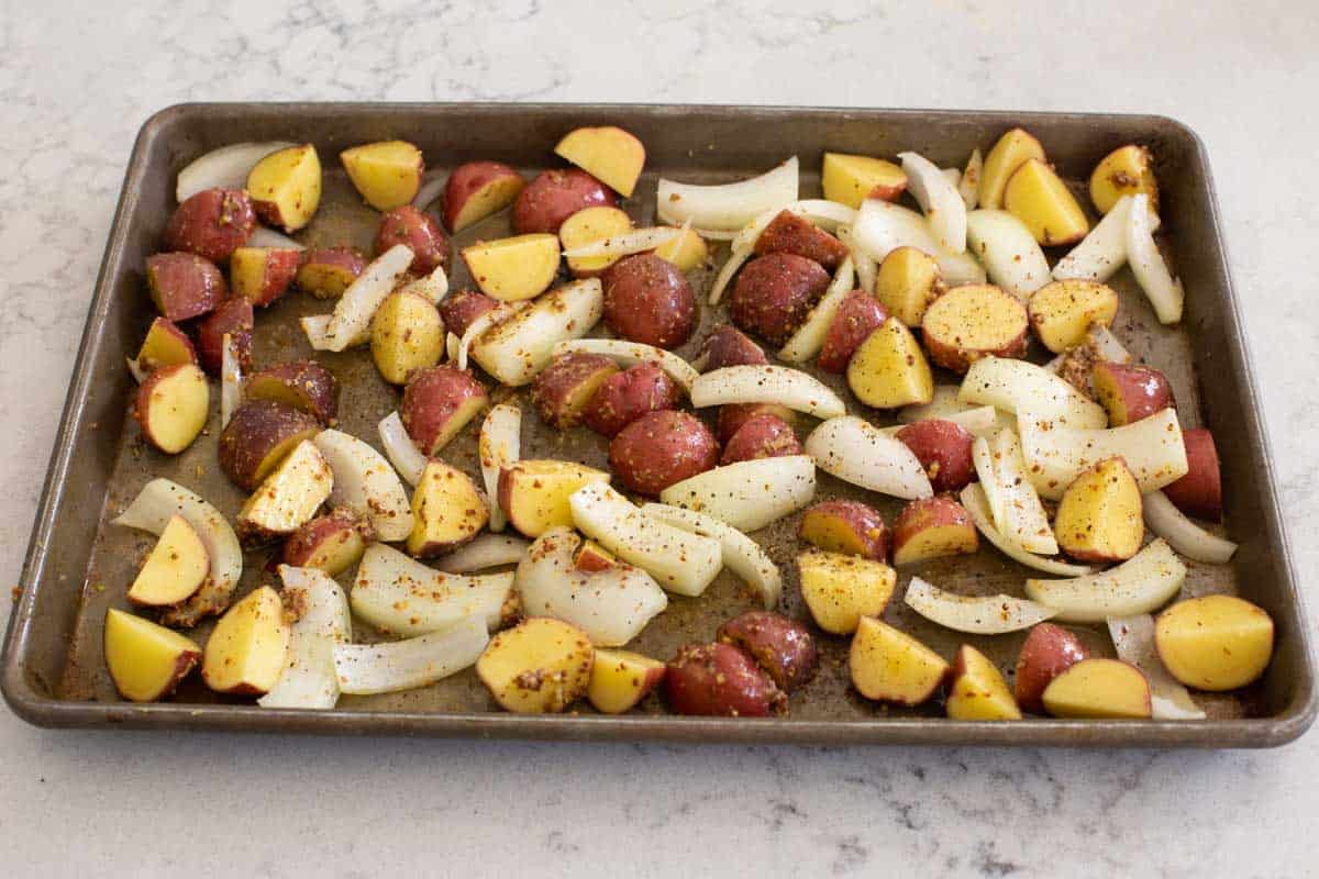 Chopped potatoes and onions on the baking sheet.