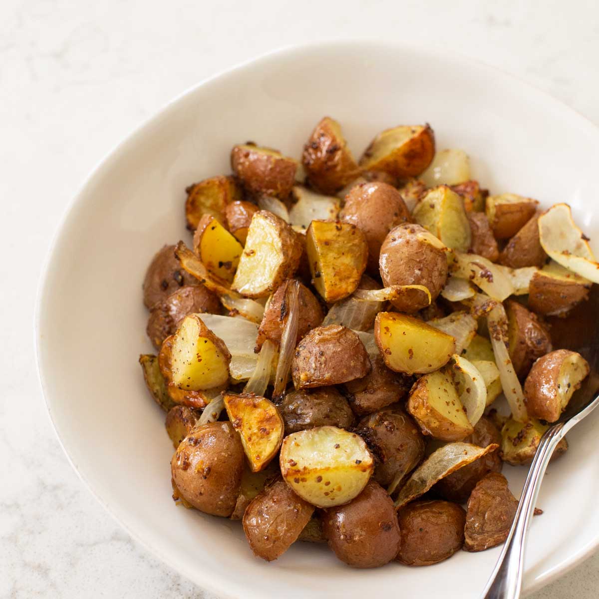 A white bowl of roasted potatoes.