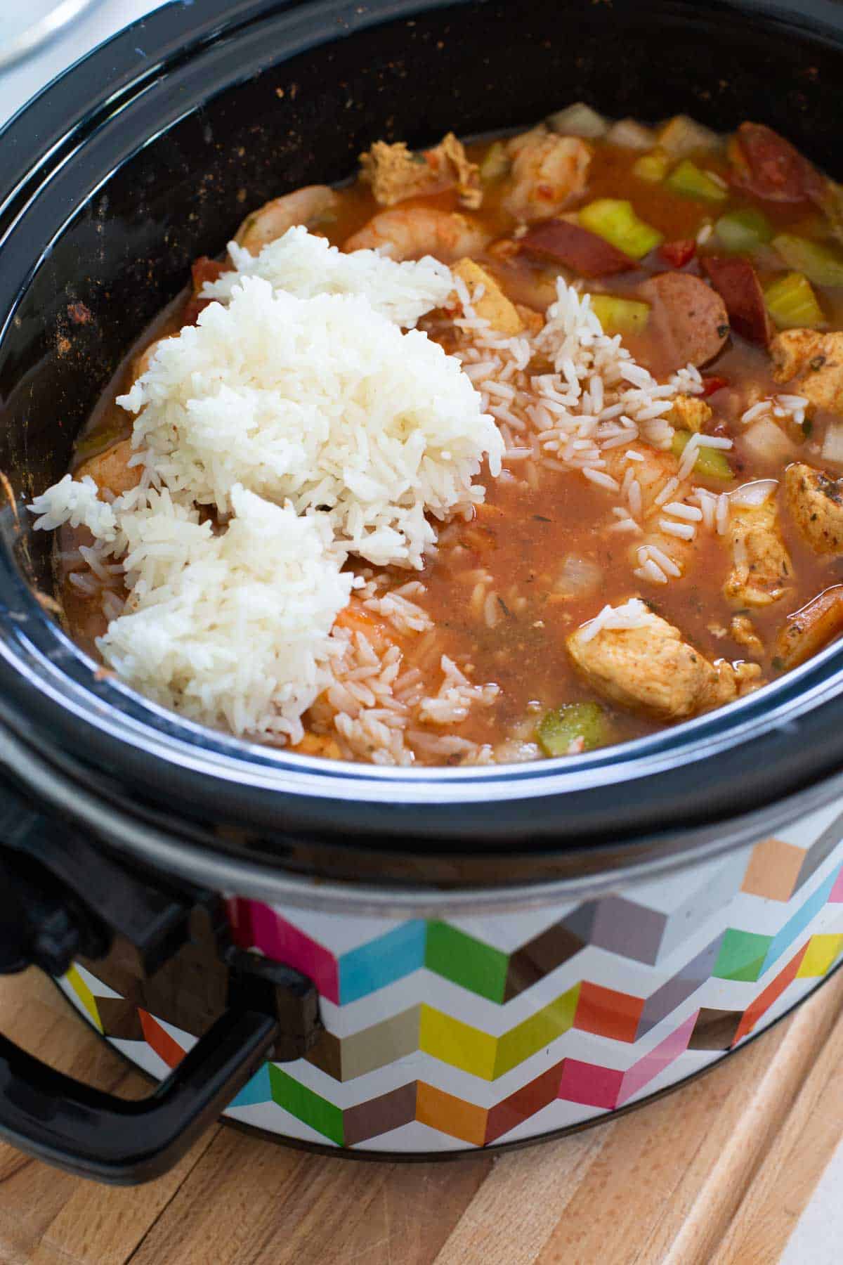 White rice is being mixed into the jambalaya.