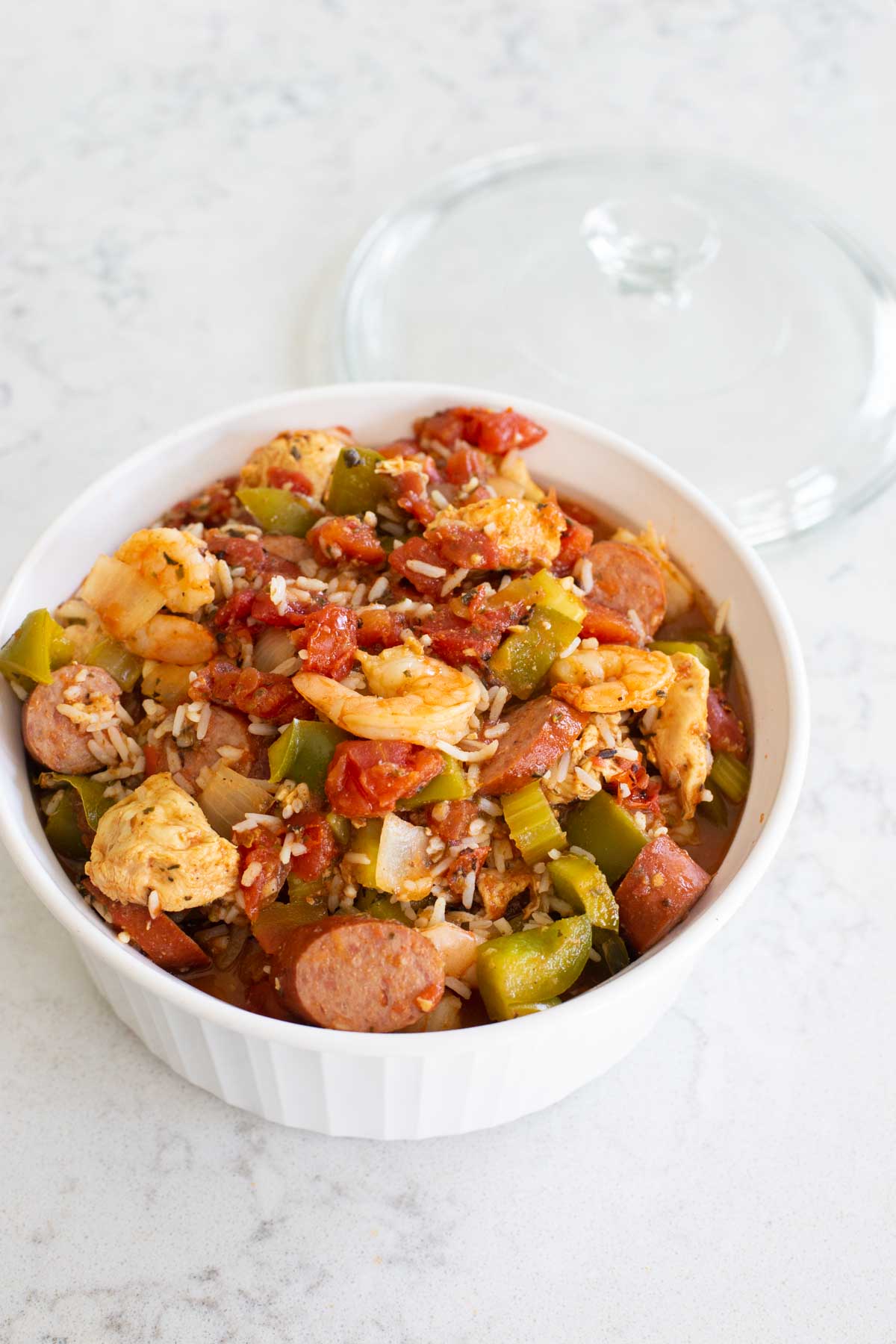 A glass casserole dish is filled with finished jambalaya for later or to bring to a friend.