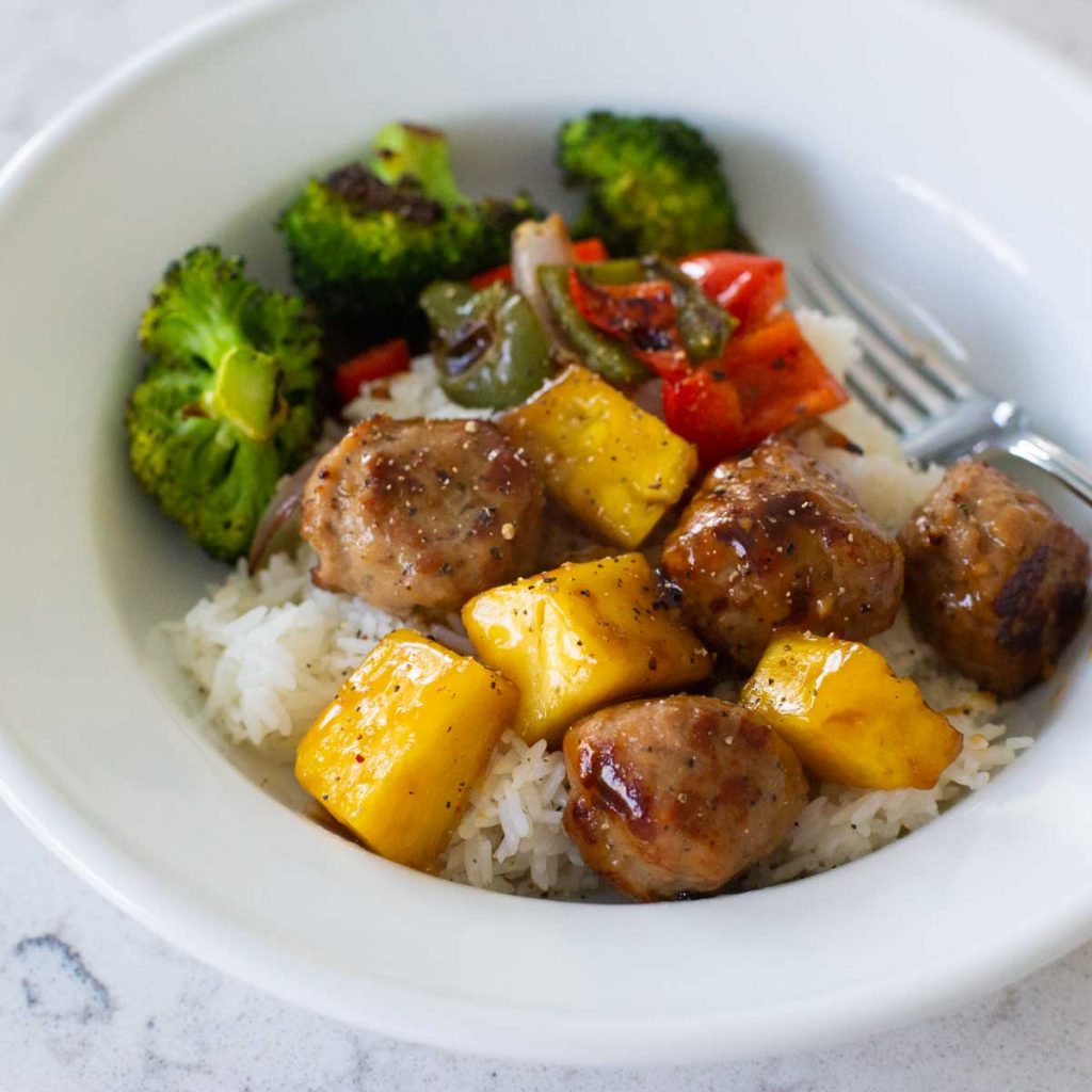 A serving of teriyaki meatballs with pineapple and vegetables over rice.