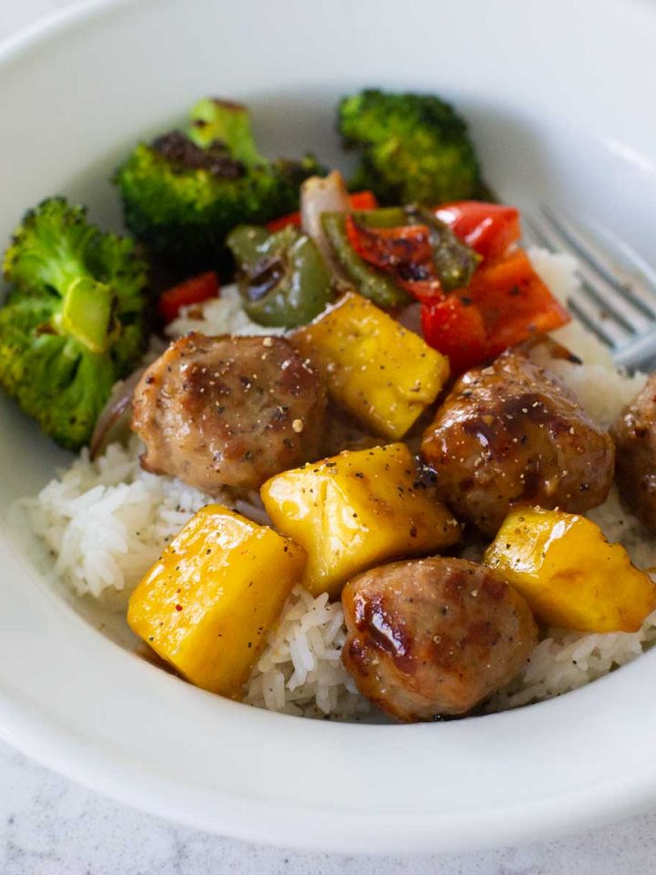 A serving of teriyaki meatballs with pineapple and vegetables over rice.