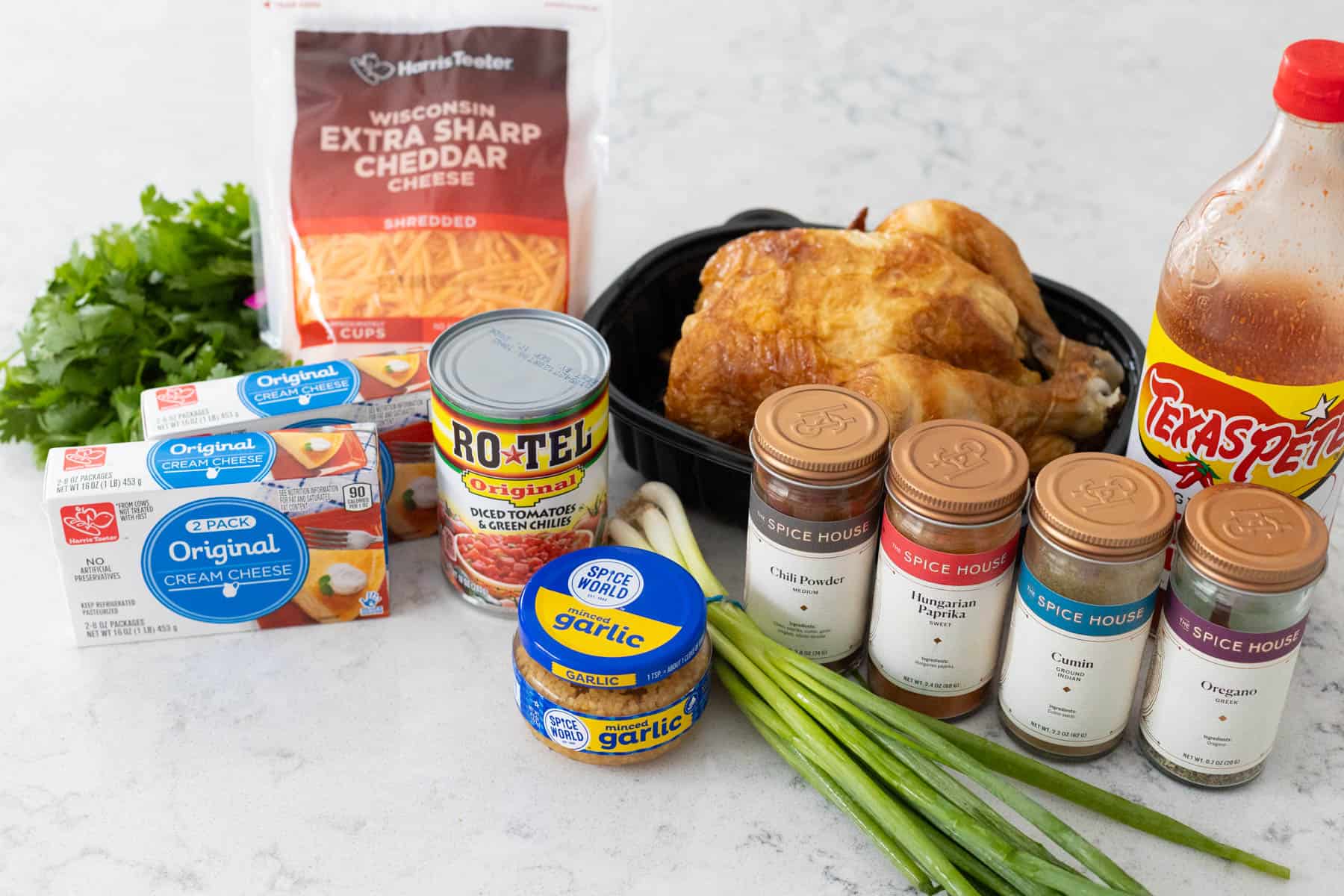 The rotisserie chicken, spices, and cheeses are on the counter.