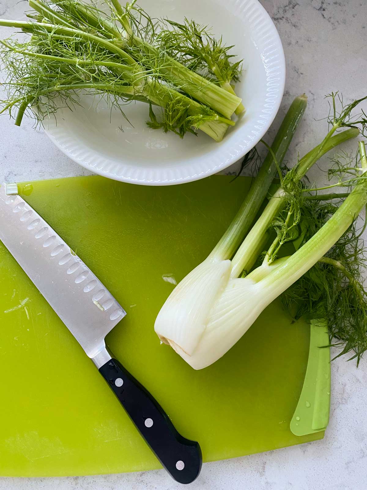 A leek is on a cutting board next to a knife.