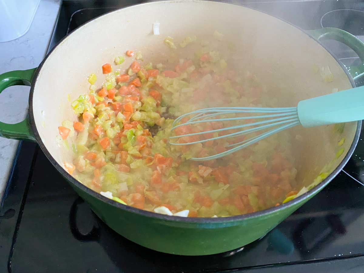 The chopped carrot, celery, leeks, and onion are sauteeing in butter in a large soup pot.