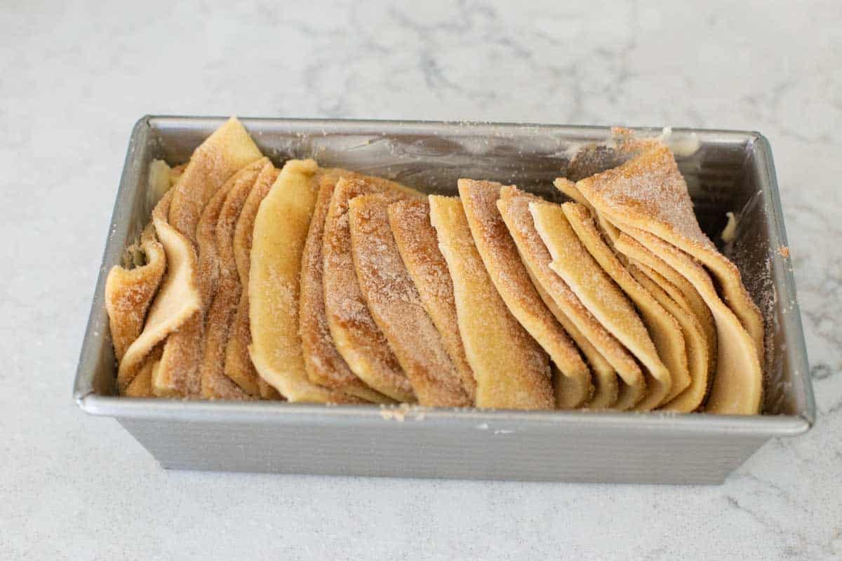 The slices of bread dough have been added to the pan cut side up like cards.