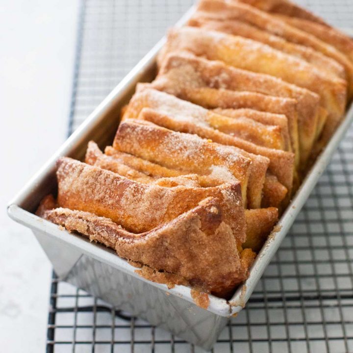 A baking pan filled with the finished cinnamon pull apart bread sits on a cooling rack.