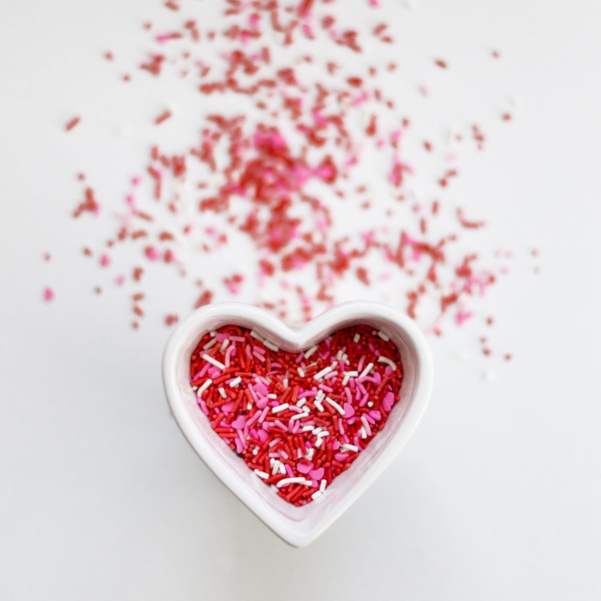 A heart shaped cup of red and pink sprinkles.