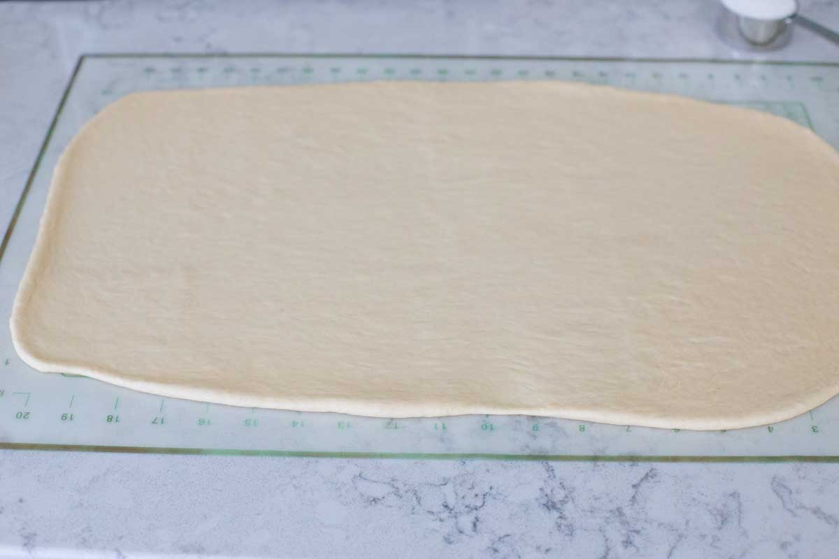 The orange roll dough should be rolled out into a rectangle with the long edge facing the baker