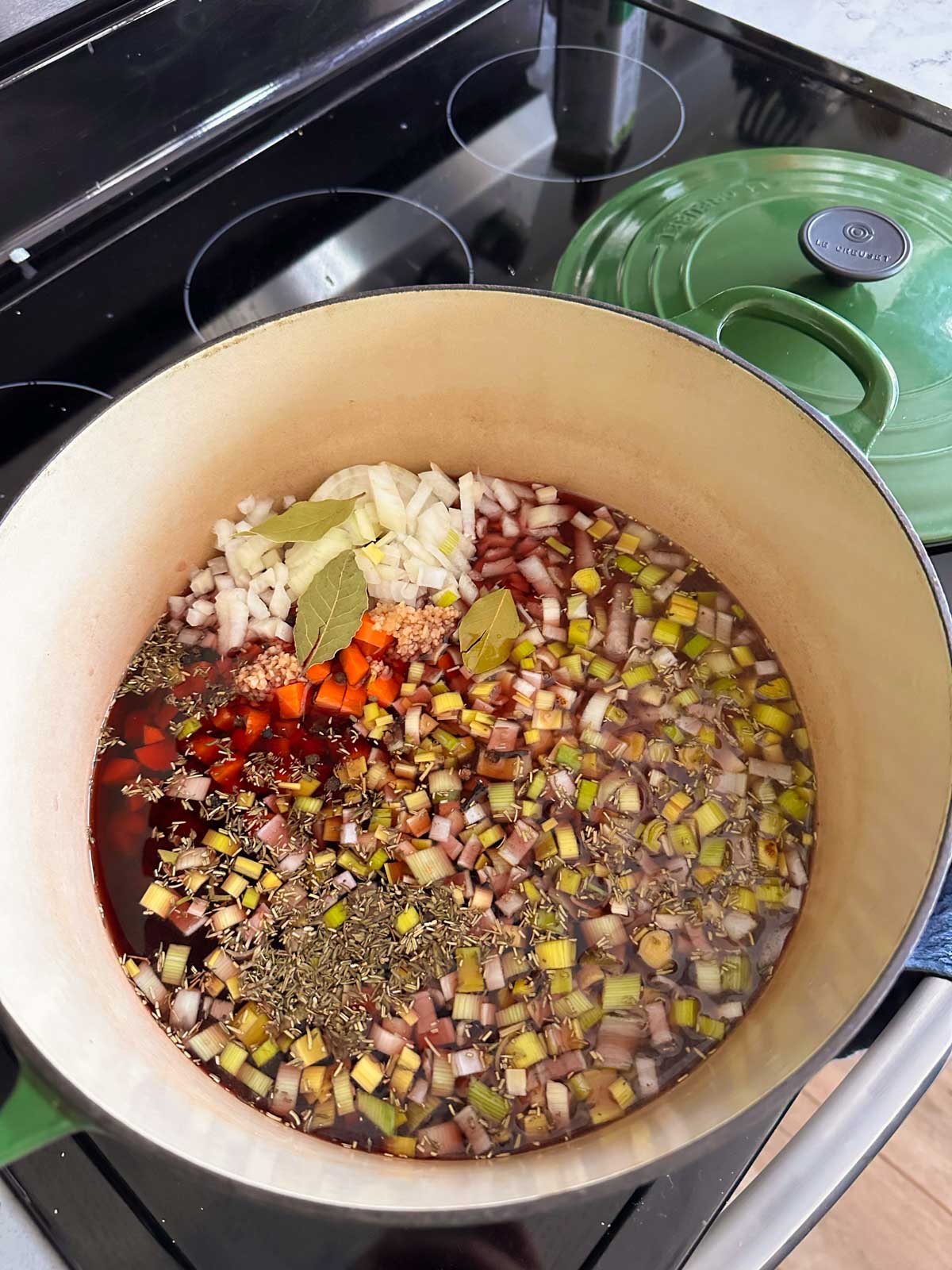 A dutch oven filled with all the ingredients for the sauerbraten marinade, ready to cook.