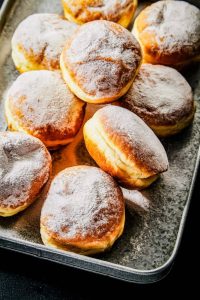 A baking pan filled with jelly donuts.