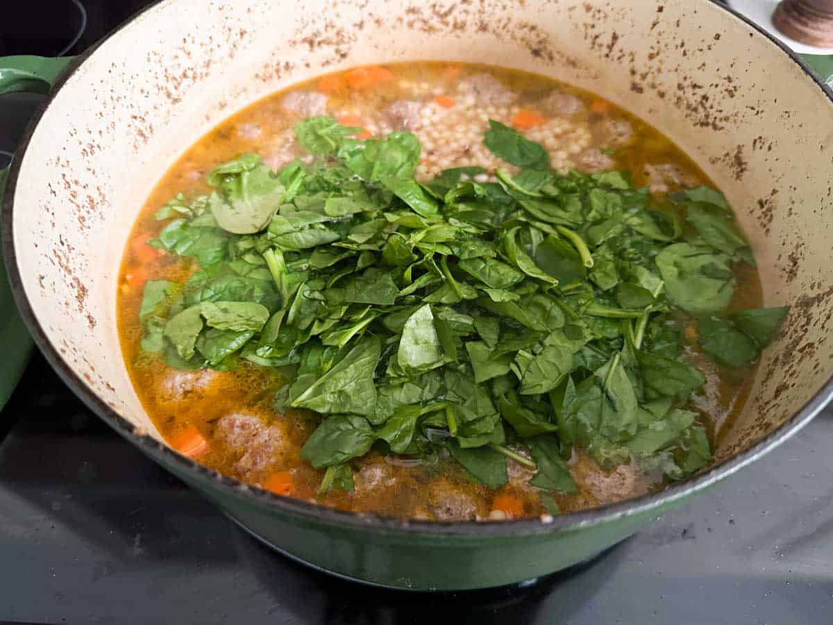 The fresh spinach is stirred into the broth.