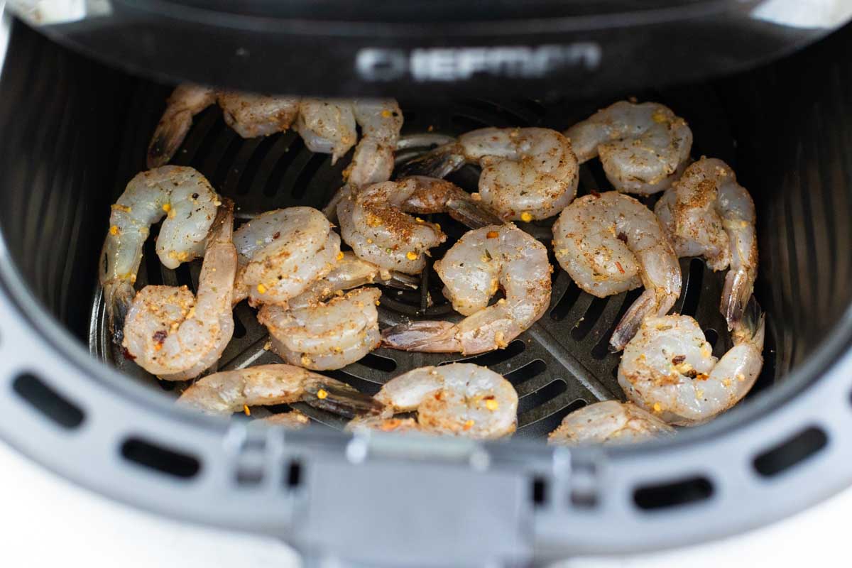 The shrimp are in a single layer in the air fryer basket.