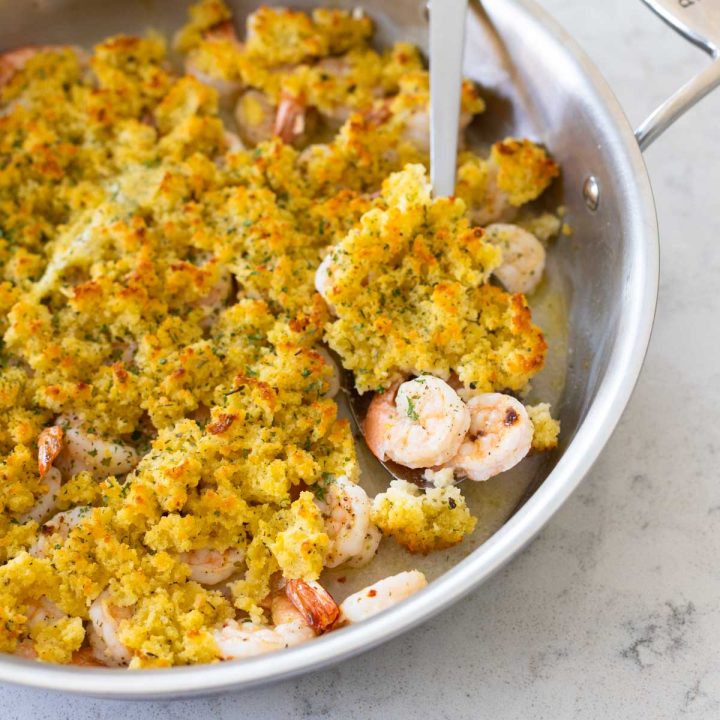 A pan with shrimp with a thick bread crumb topping over the top.