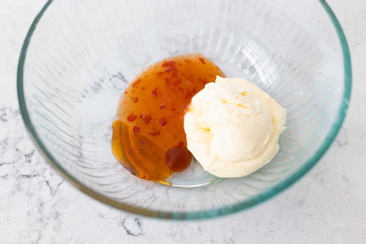 The chili sauce and mayo have been added to a mixing bowl.