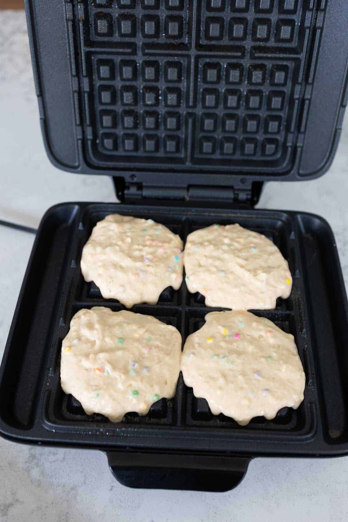 1/3 cup waffle batter has been added to 4 wells on a waffle maker.