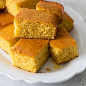 A white ruffled platter has large squares of homemade buttermilk cornbread.