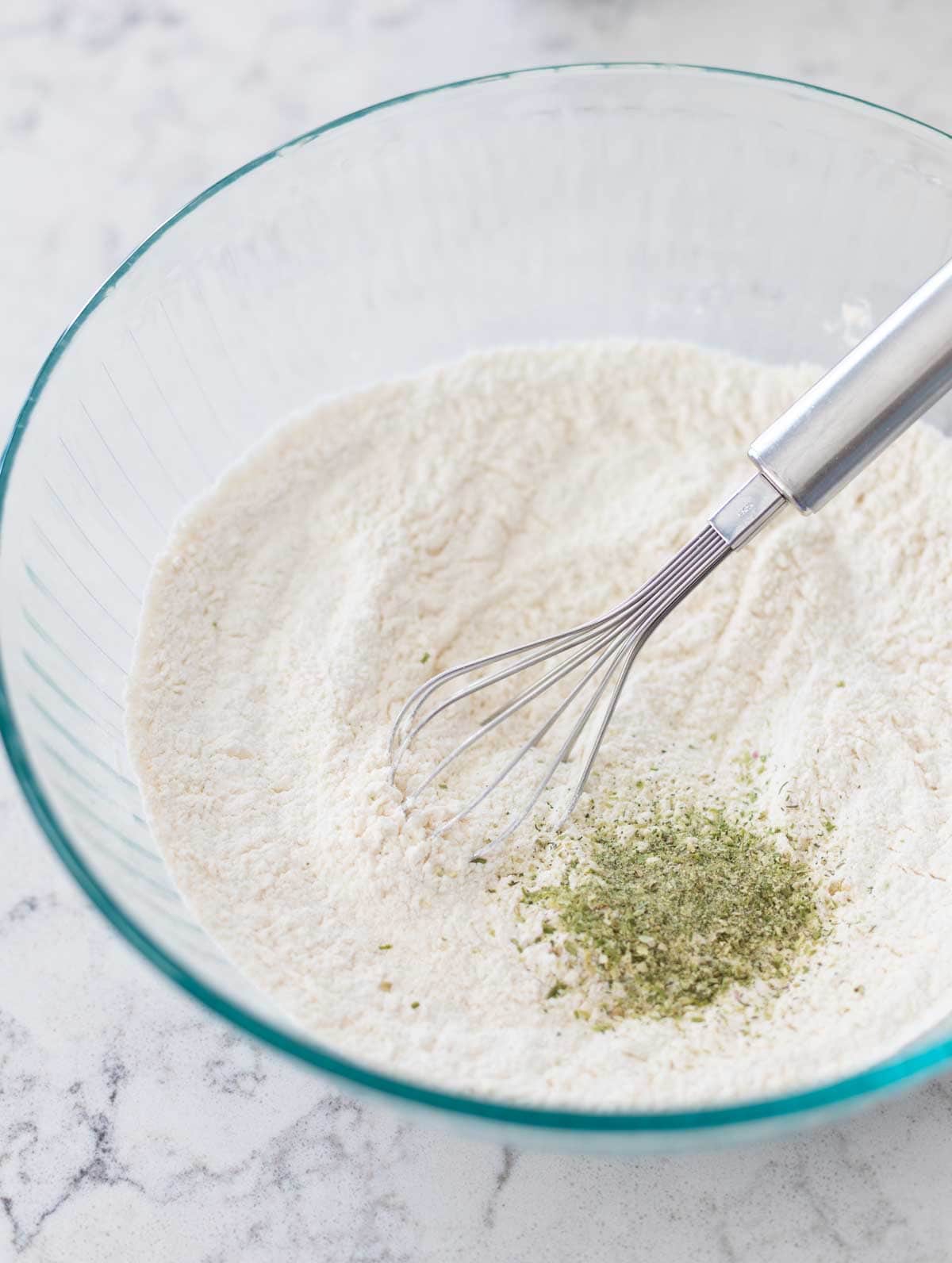 The flour and baking powders have been whisked together and the green herbs have just been added to the bowl.