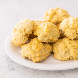 A white plate has a pile of fresh baked buttermilk drop biscuits.