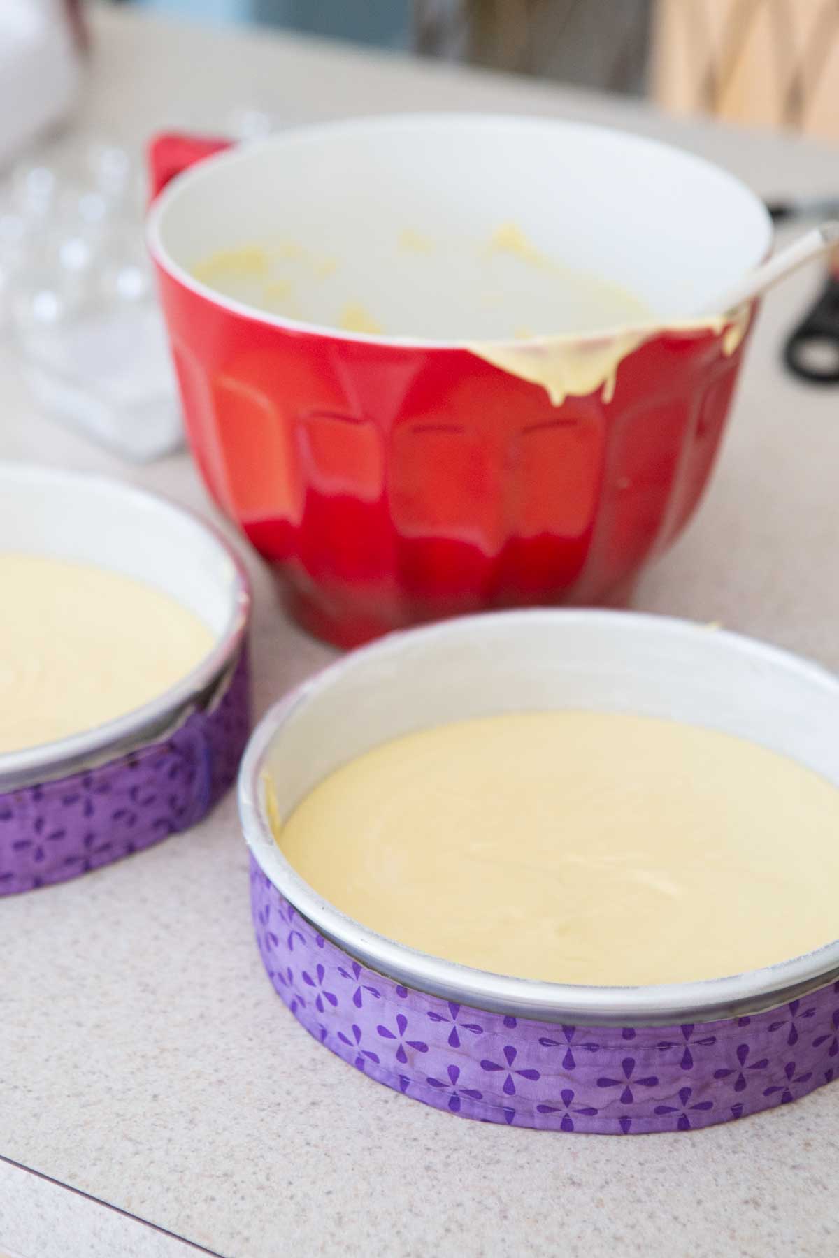 The cake pans have been wrapped in cake strips and the cake batter has been poured inside.