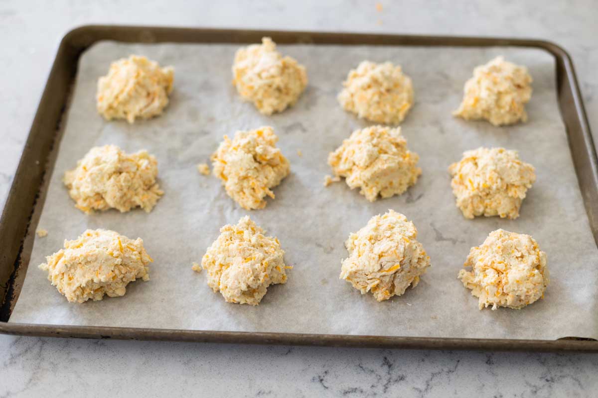 A baking pan lined with parchment shows how to space the biscuits.