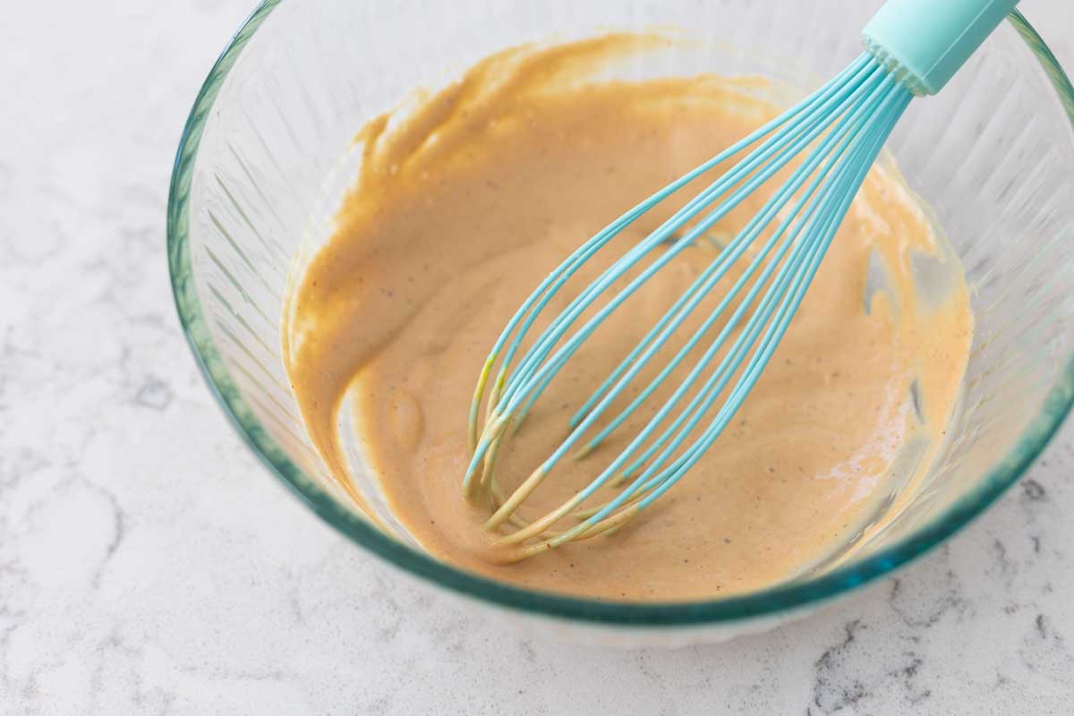 The sauce has been whisked together with a blue whisk resting in the bowl.