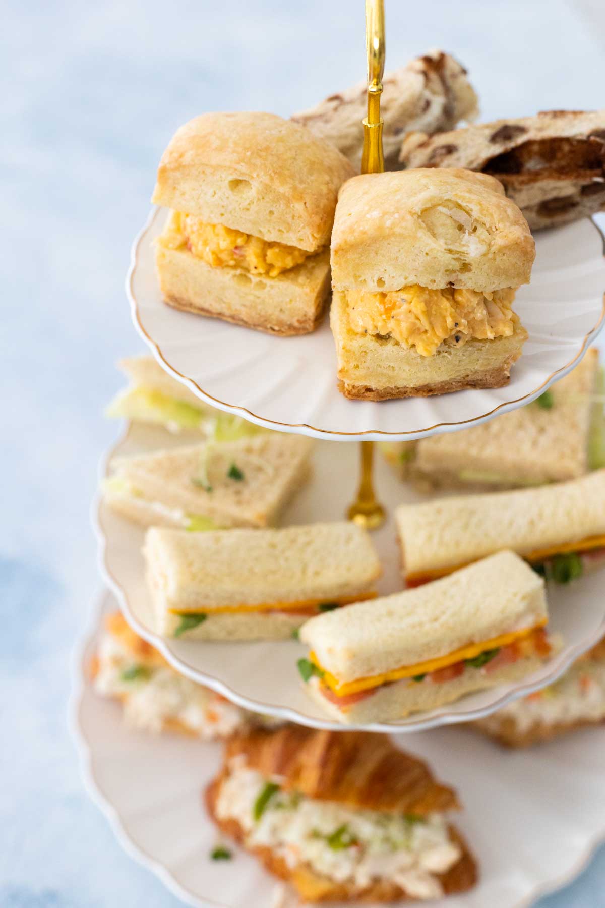 A 3-tier tray is filled with a variety of finger sandwiches.