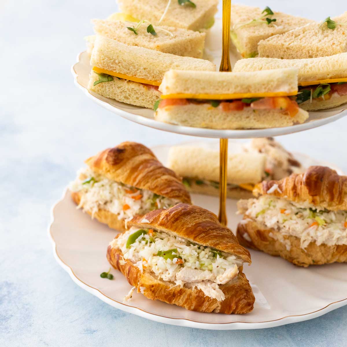 A tiered sandwich tray has several finger sandwiches on display.