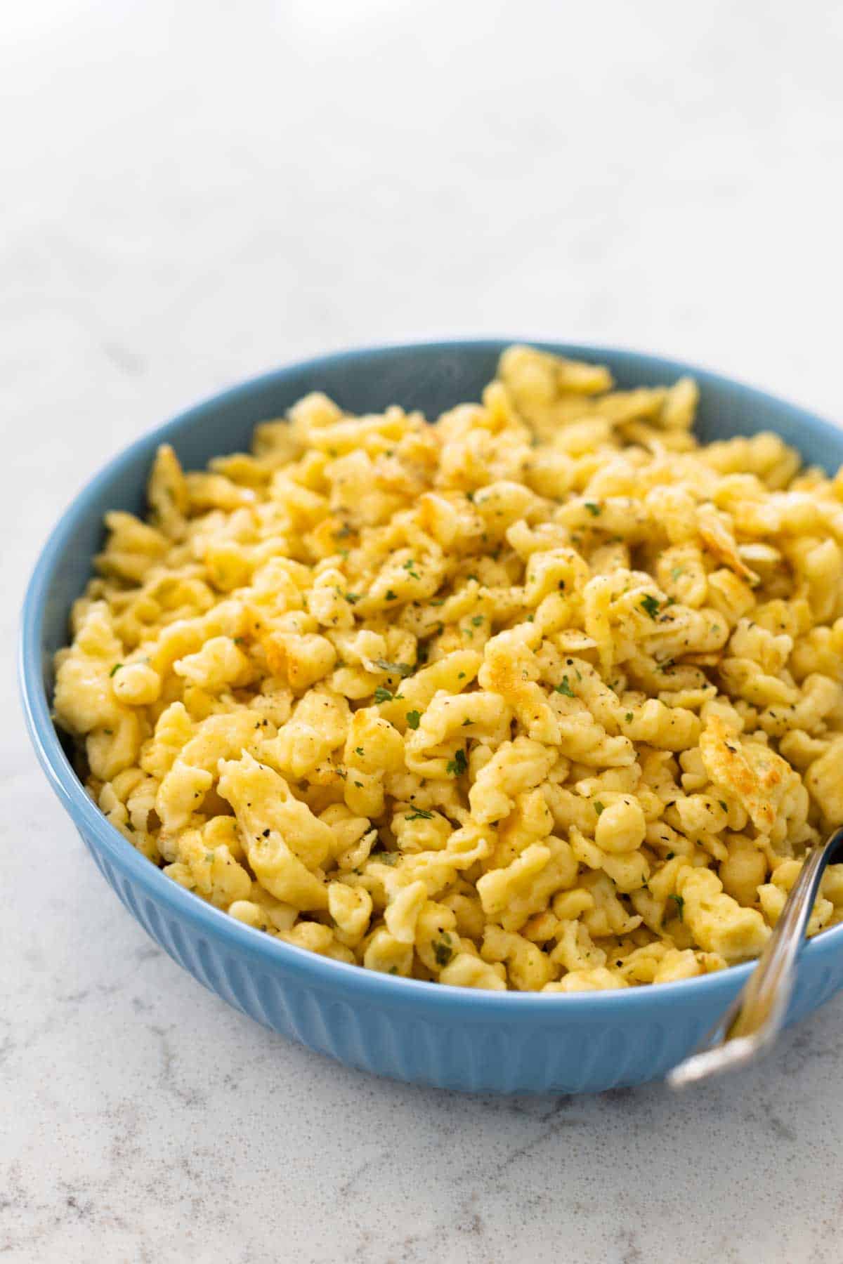 The finished spaetzle are being served for dinner in a blue bowl.