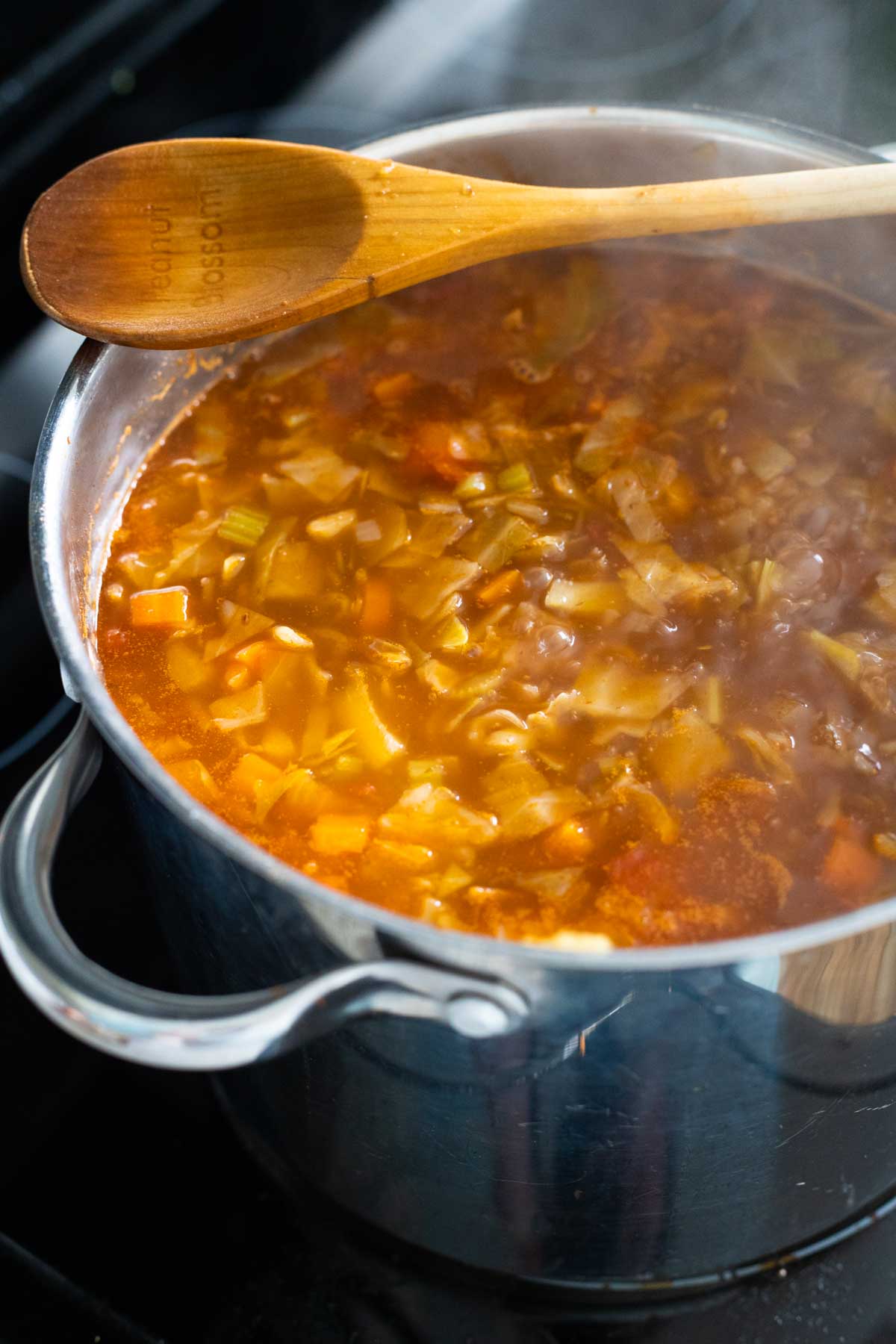 The finished soup is still in the soup pot with the wooden spoon off to the side.