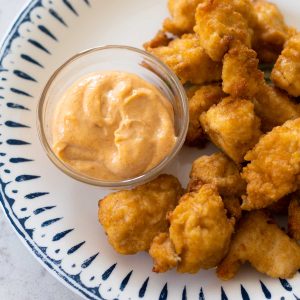 The yum yum sauce is in a dipping cup on a plate with chicken nuggets.