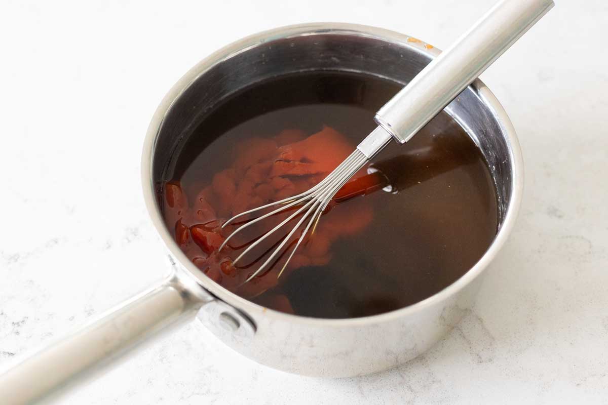 The saucepan has the ingredients for the sweet and sour sauce being whisked together.