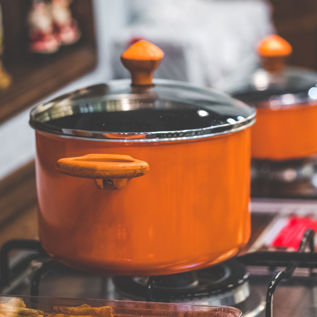 An orange pot on the stovetop is cooking a family dinner.