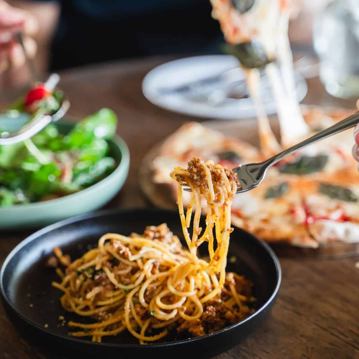 A fork takes a bite of spaghetti at family dinner.