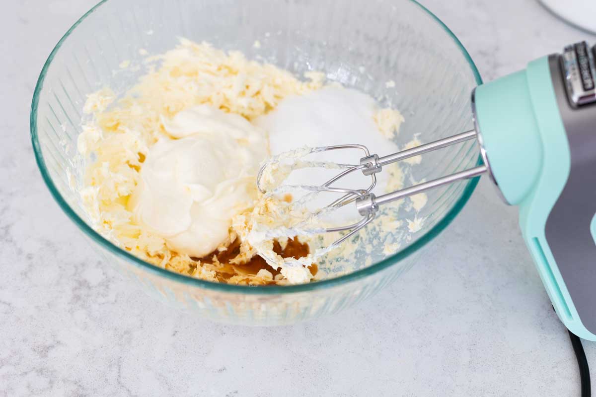 The cream cheese, sugar, vanilla, and sour cream are in a mixing bowl.