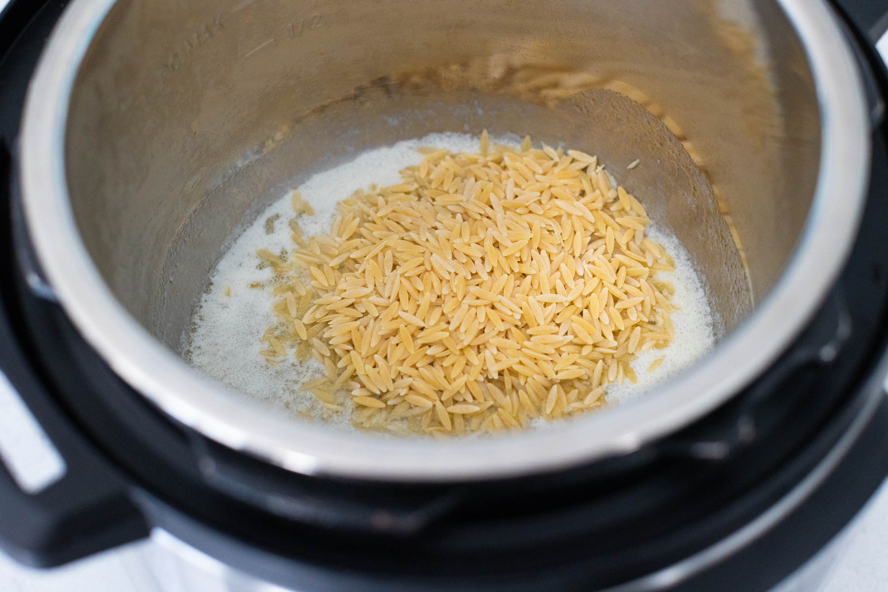The butter has been melted in the Instant Pot and now the orzo is being stirred in.