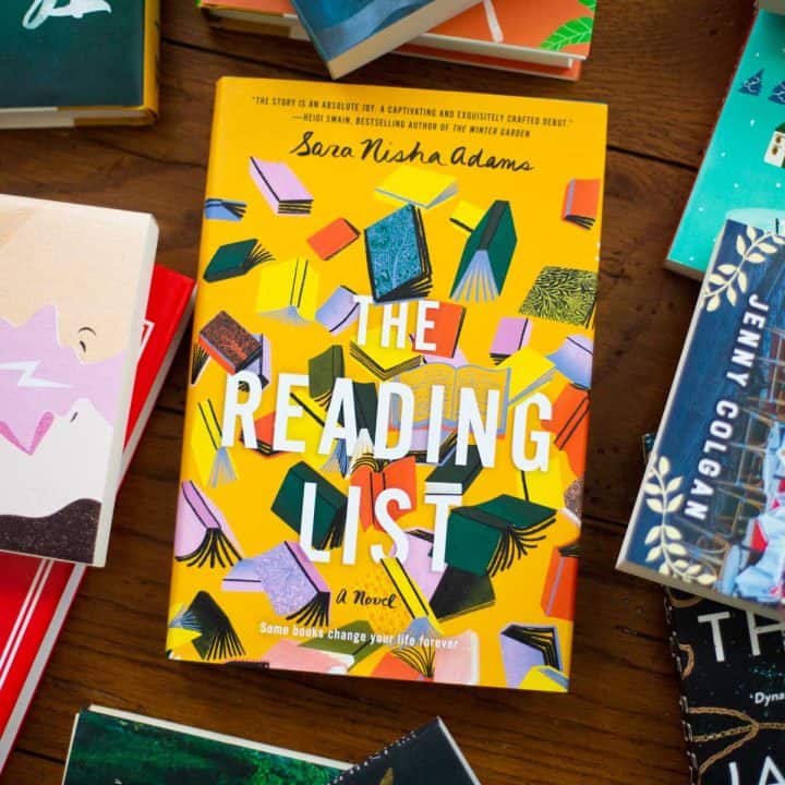 A copy of The Reading List sits on a table surrounded by other books.